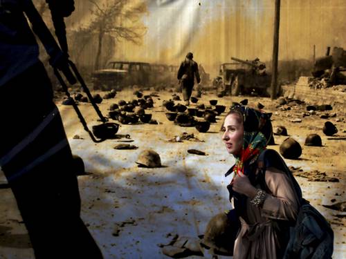 Mulher passa por cartaz em Teerã com imagem da guerra entre Irã e Iraque na década de 80 Ebrahim Noroozi - AP